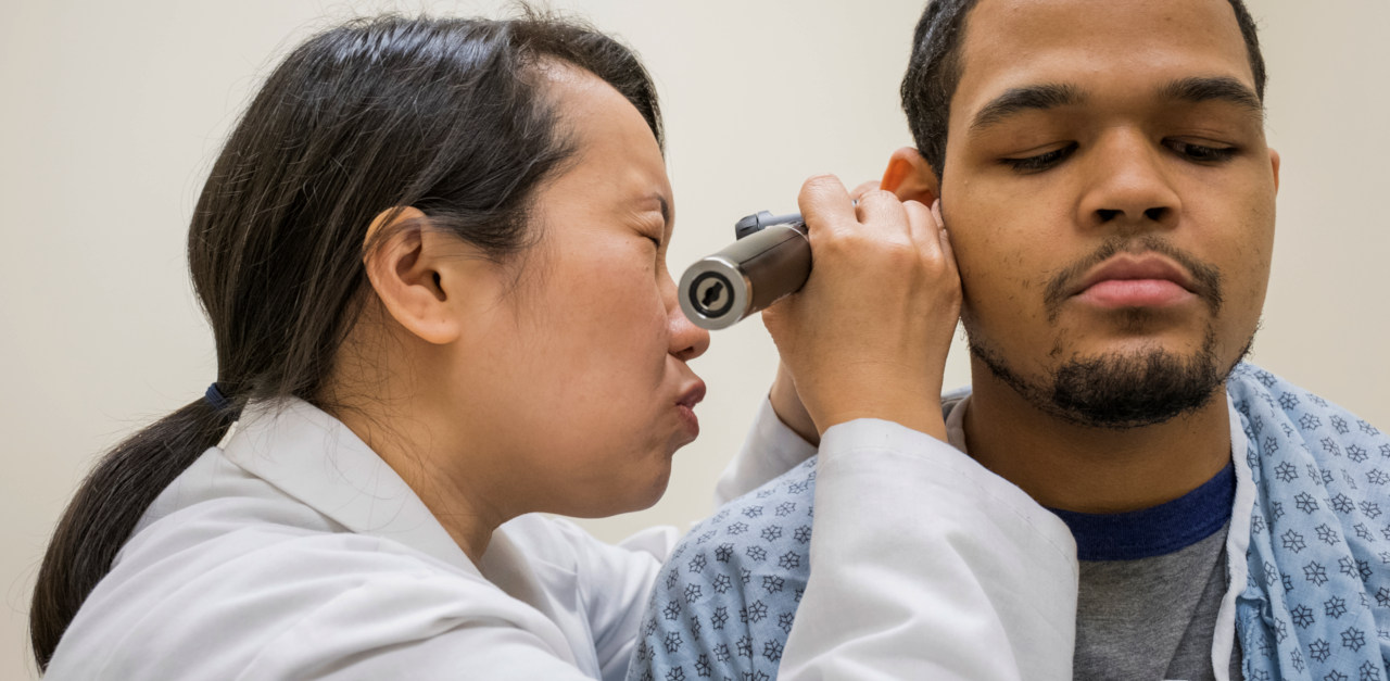 A nurse examines a patient ear with an otoscope