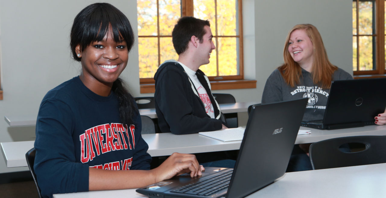 Student with Detroit Mercy sweatshirt in class with laptop.