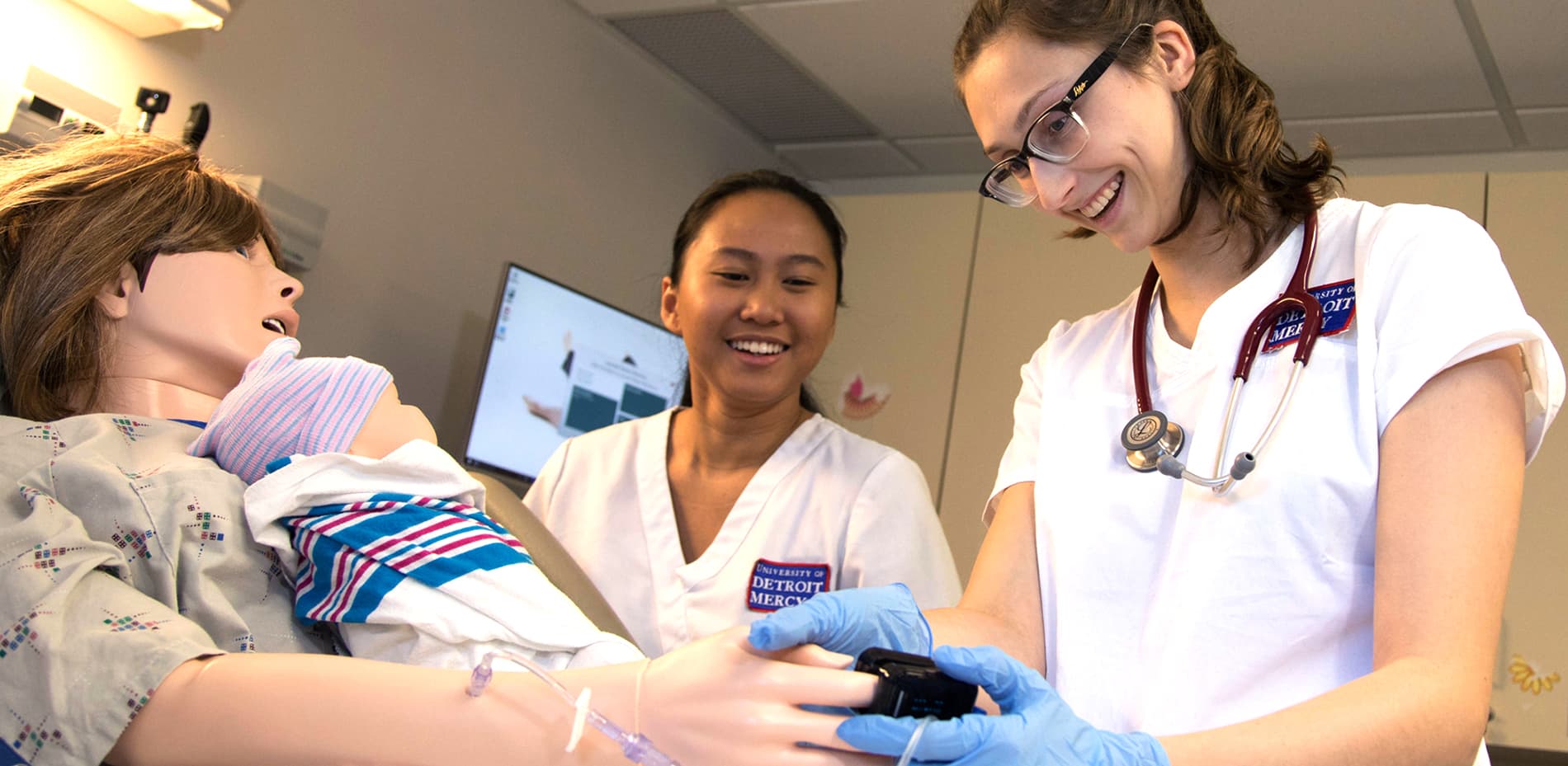 Nursing students examine a dummy.