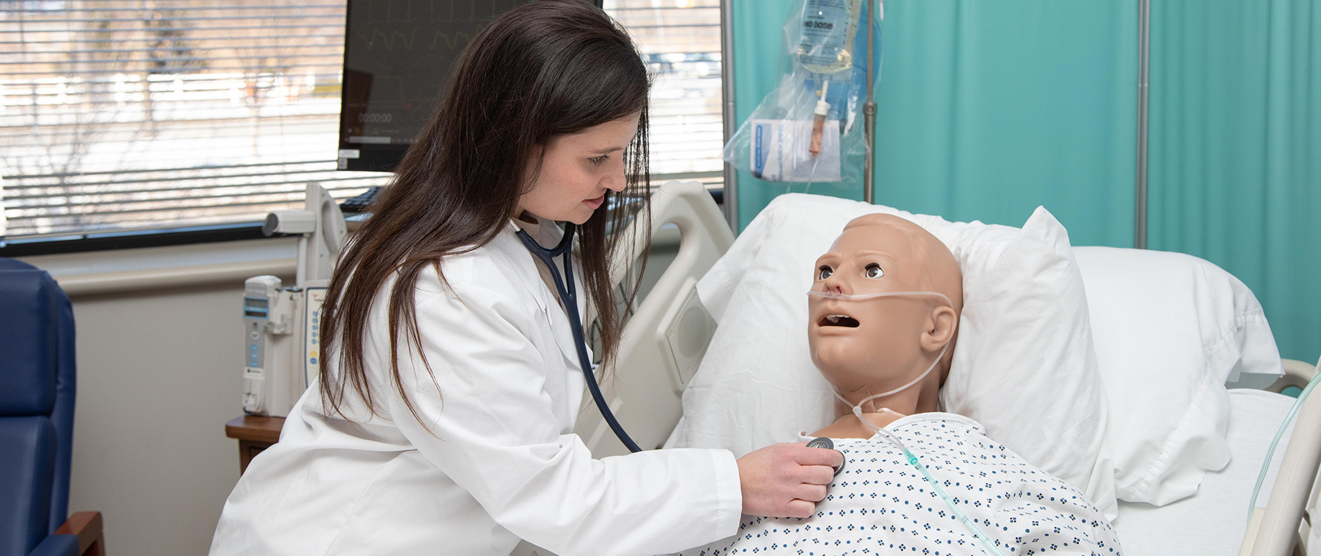 a student simulates using a stethoscope on a manikin