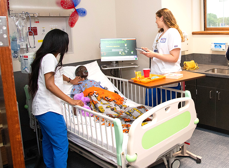 two students in the sim-suite with youth manikin