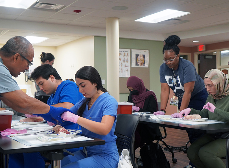 PA students practicing suturing with help of instructors
