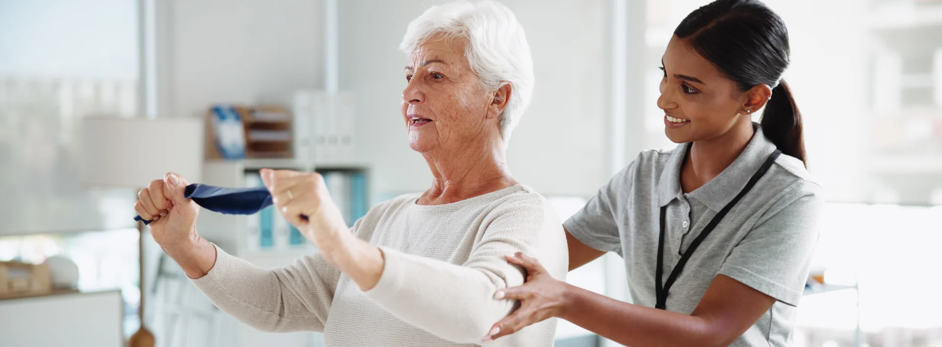 Young physical therapist assists a senior patient with arm exercises.