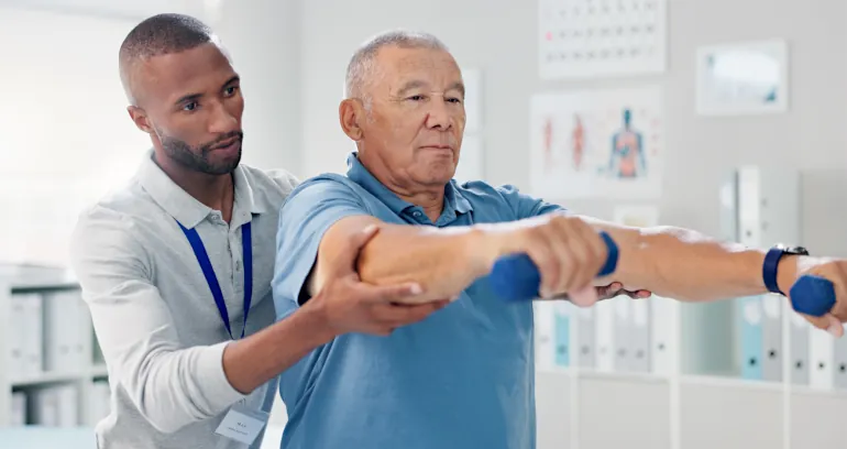 A physical therapist assists a man with an arm exercise