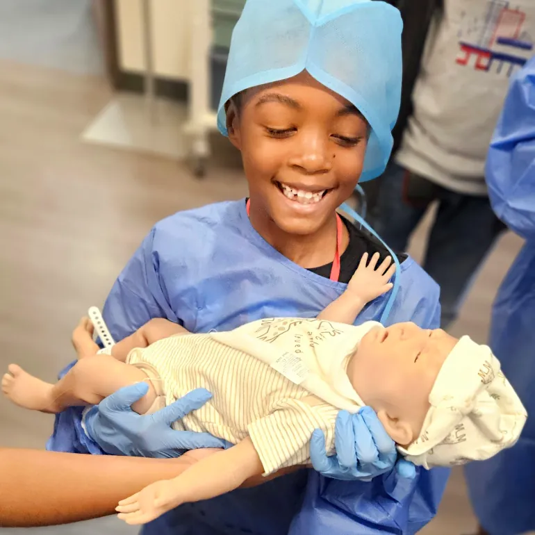 Smiling boy holding infant simulation manikin