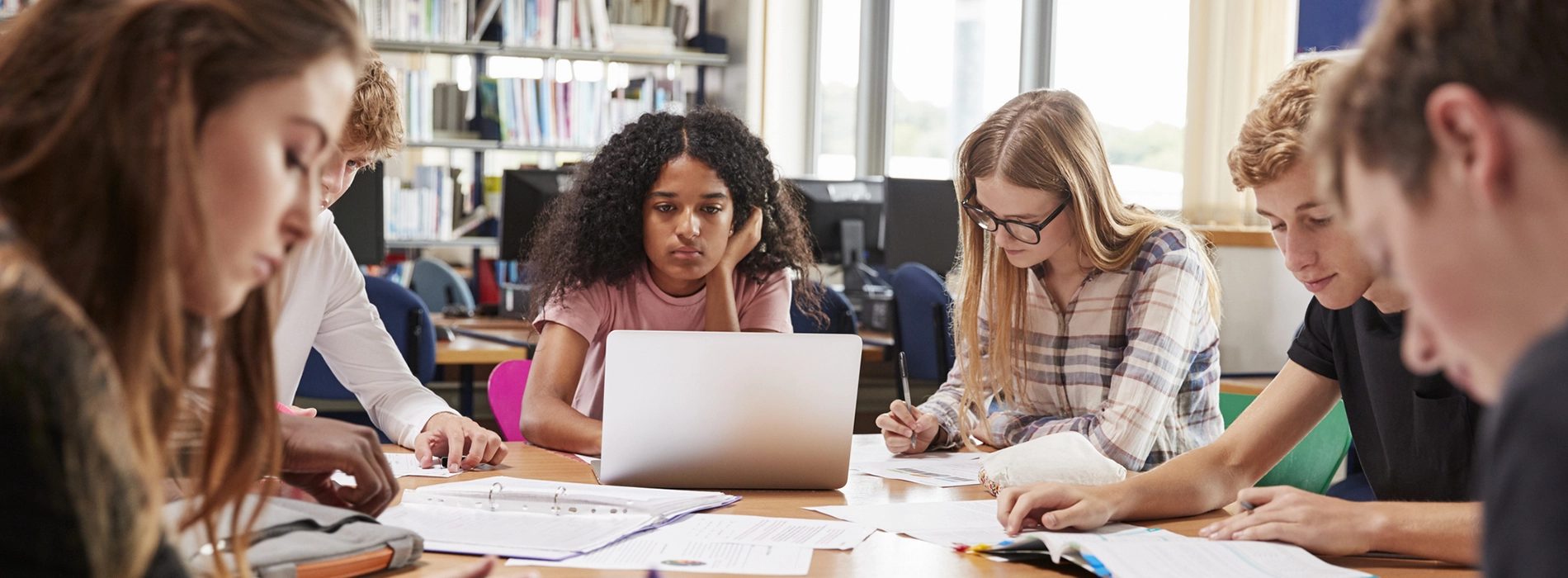 A group of students studying together at a table in a library.